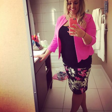 jen wearing a hot pink blazer and printed skirt, taking a mirror selfie 